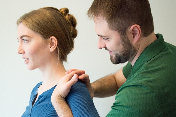 Dr. Stewart conducting a standing shoulder adjustment for a female patient.