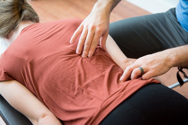 Dr. Mason Stewart, DC activates a back muscle on a female patient in Post Falls, ID.