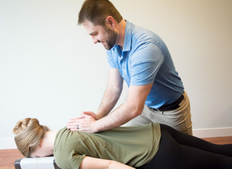 Dr. Mason Stewart, DC of New Leaf House Call Chiropractic in Post Falls, ID provides Chiropractic Care by adjusting the upper back of a female patient.