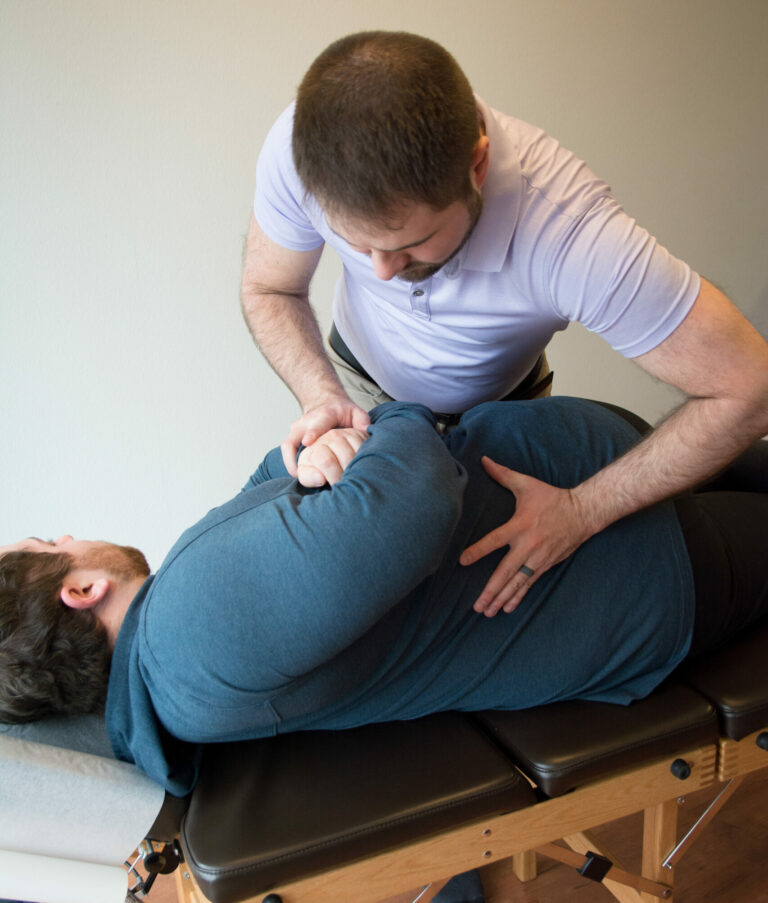 Dr. Mason Stewart, DC of New Leaf House Call Chiropractic in Post Falls, ID provides Chiropractic Care by adjusting the spine of a male patient in side posture.