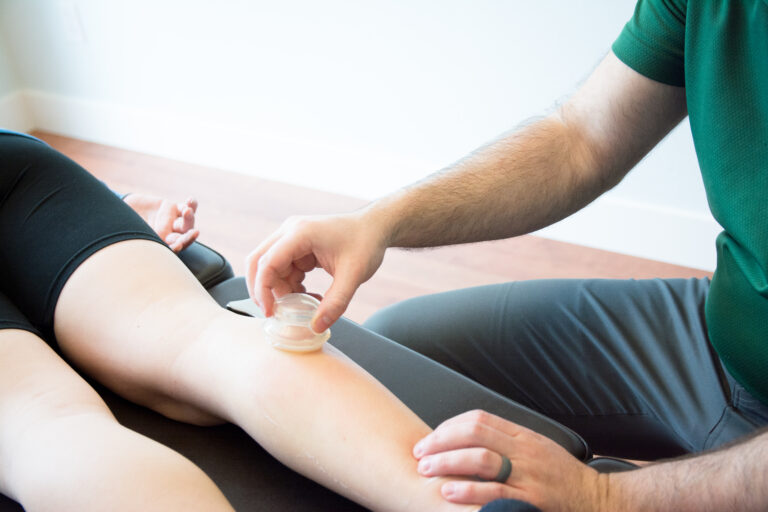 Dr. Mason Stewart, DC of New Leaf House Call Chiropractic in Post Falls, ID administers cupping on the calf of a female patient.