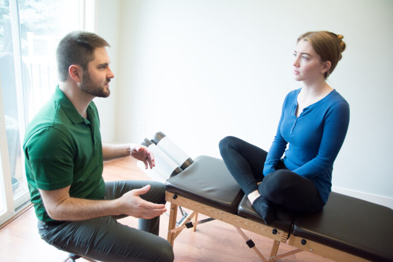 Dr. Mason Stewart, DC discusses chiropractic and muscle activation with a female patient in Post Falls, ID.