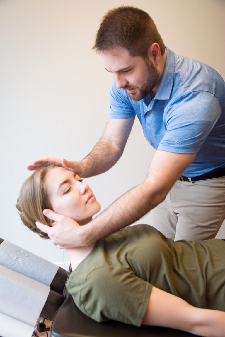 Dr. Mason Stewart, DC tests a neck muscle on a female patient in Post Falls, ID.