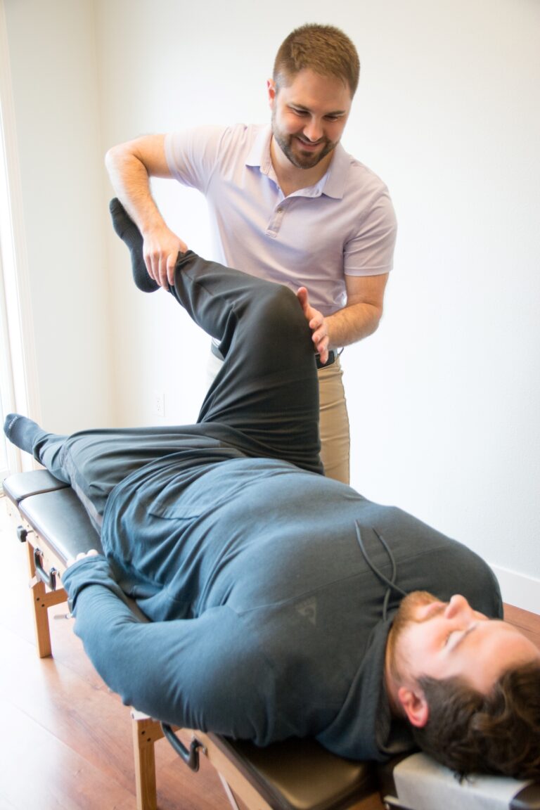 Dr. Mason Stewart, DC tests a leg muscle on a male patient in Post Falls, ID.