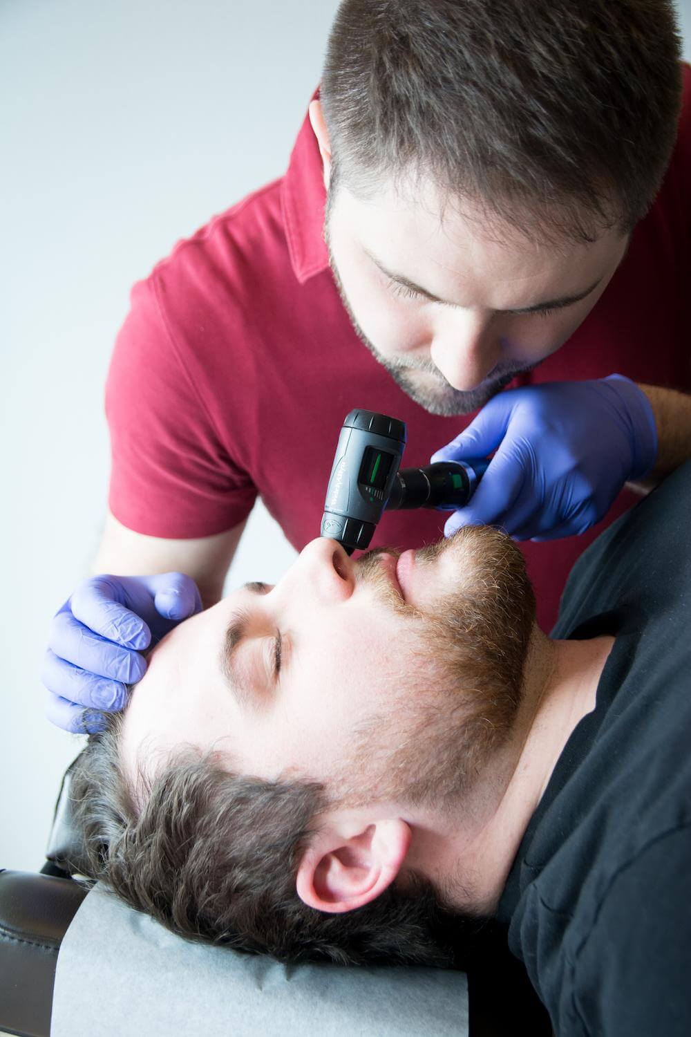 Dr. Mason Stewart, DC of New Leaf House Call Chiropractic in Post Falls, ID conducts a Nasal Specific Technique examination on a male patient.