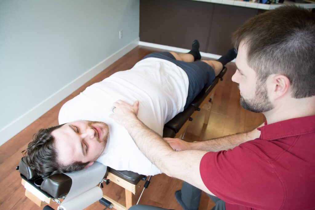 Dr. Mason Stewart activating a chest muscle on an athletic male patient.