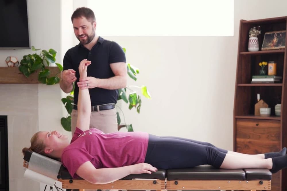 Dr. Mason Stewart testing a female patient's shoulder muscle.