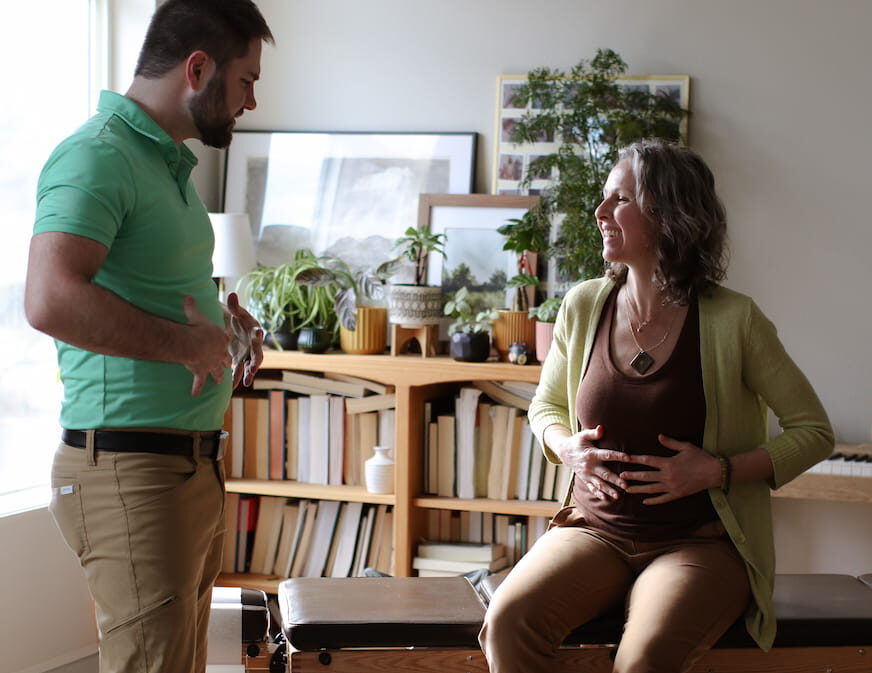 Dr. Mason Stewart demonstrating to a female patient how to breathe with the belly as part of the breath training for the Breathe Better Treatment.